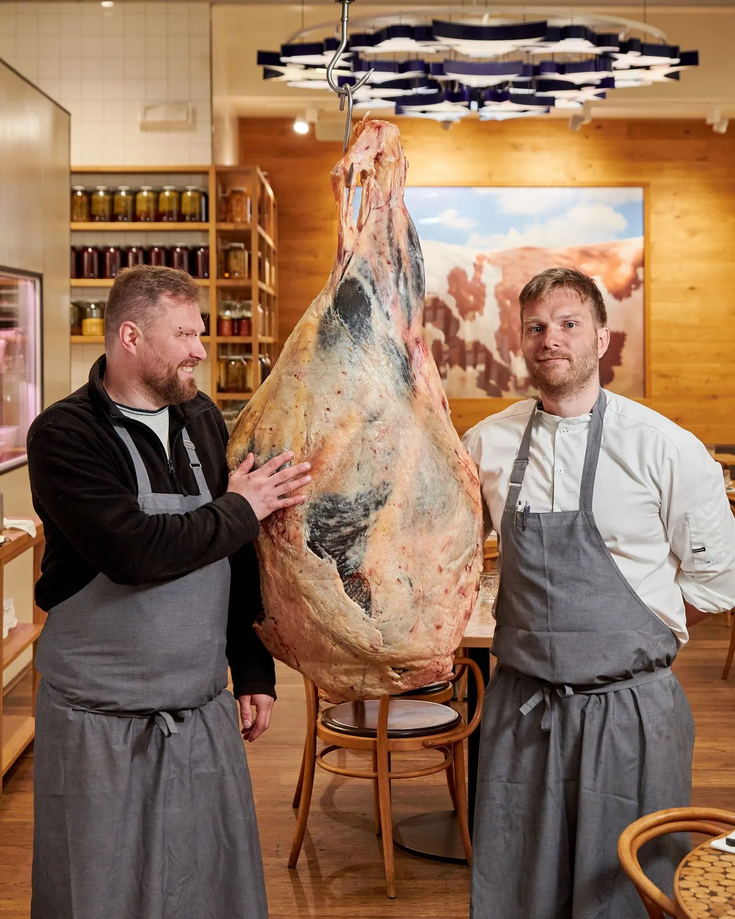 Chefs at Čestr restaurant with a dry-aged beef quarter hanging in the restaurant interior.